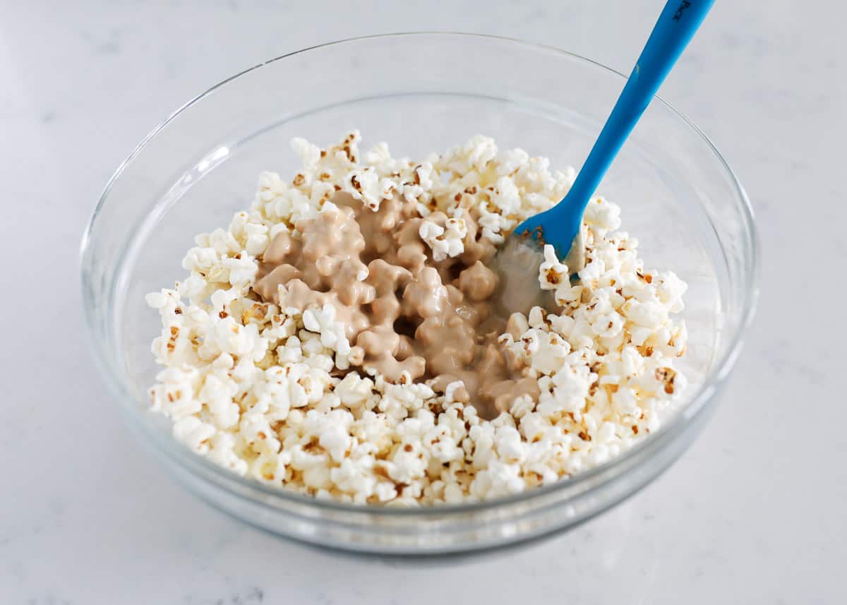 mixing popcorn and cookie butter in bowl