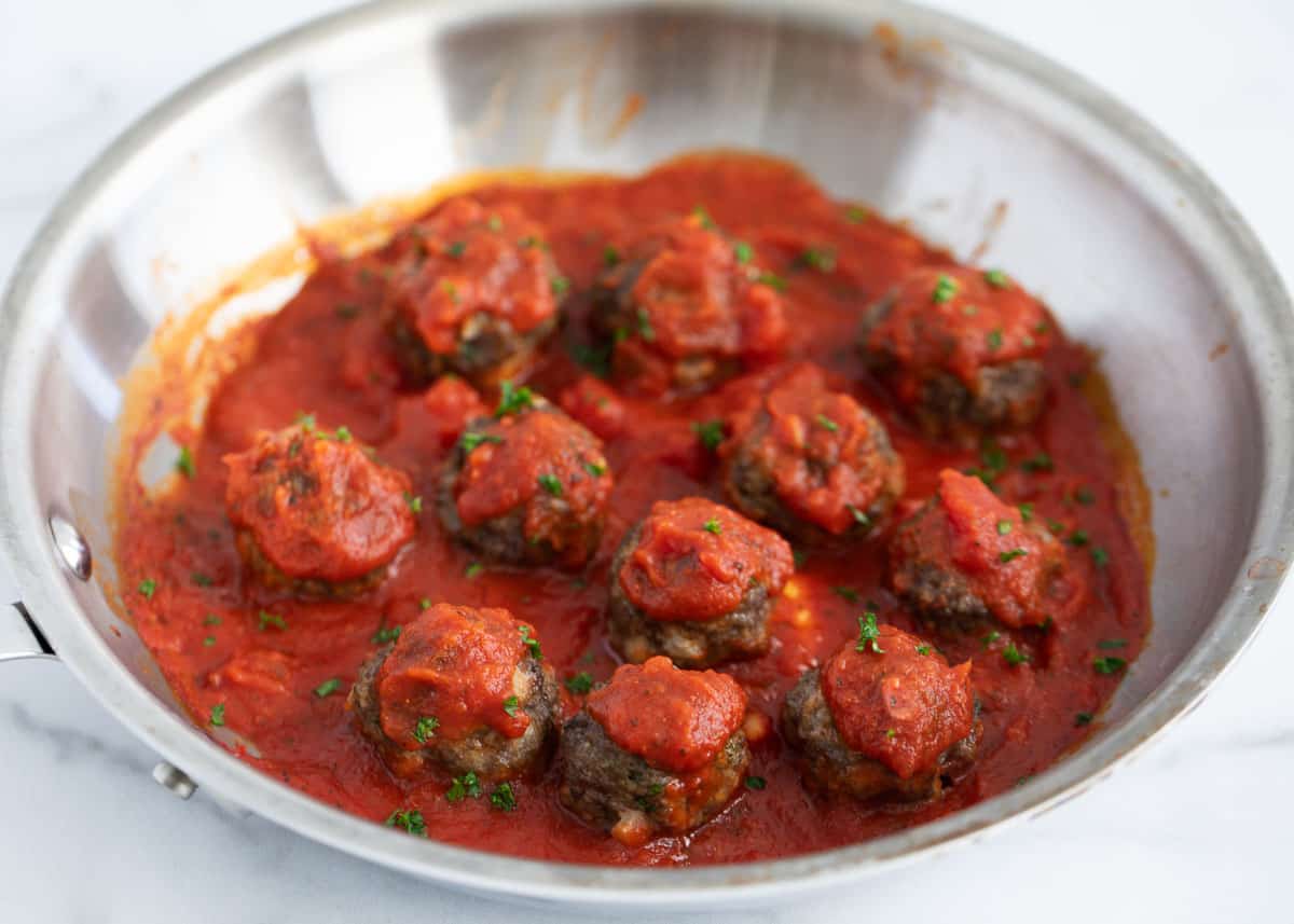 Meatballs in marinara sauce in skillet.