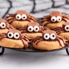 Halloween spider cookies made with peanut butter cookies on black plate.