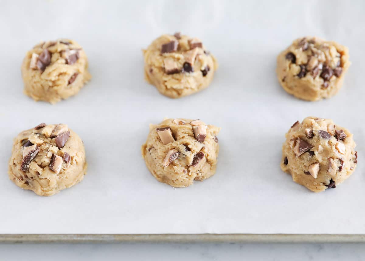 Toffee cookie dough balls on baking pan lined with parchment paper.