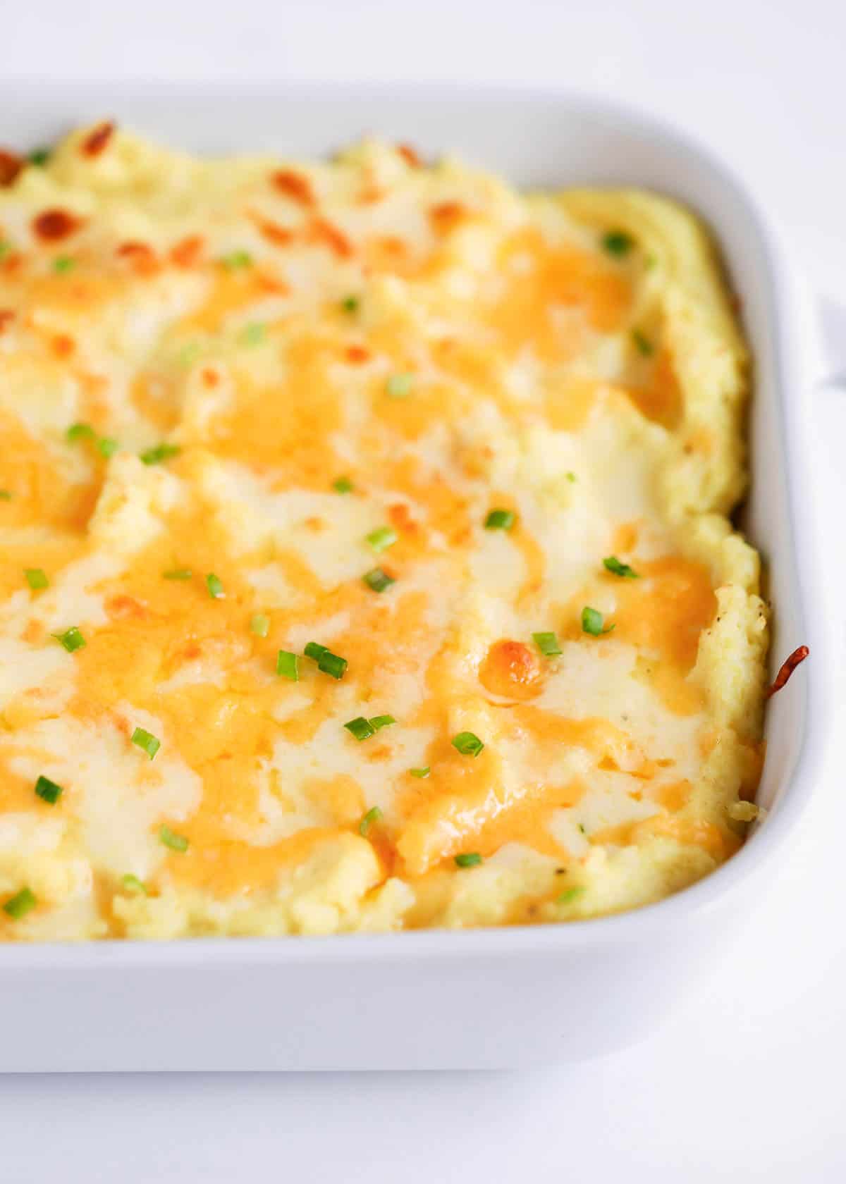 Cheesy mashed potatoes in a white dish.