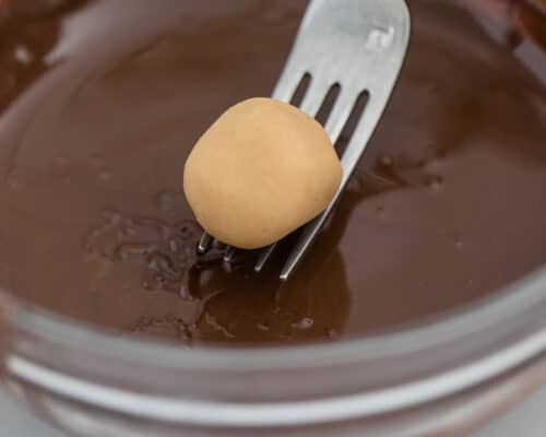 dipping peanut butter ball into chocolate