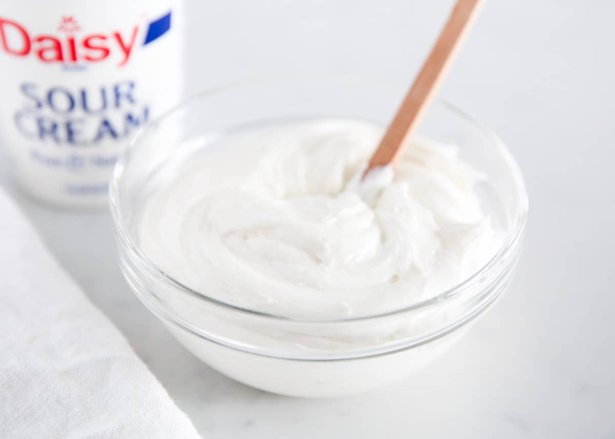 Sour cream frosting in a bowl with spoon.