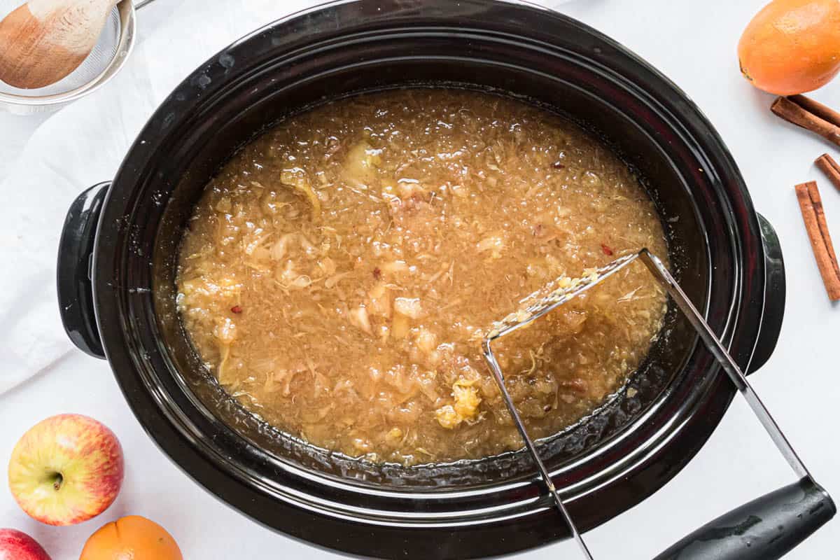 Mashing fruit in crock pot for apple cider.