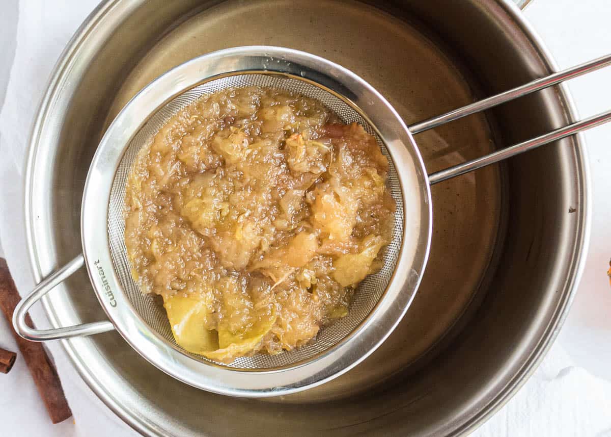 Straining fruit in mesh strainer for slow cooker apple cider.