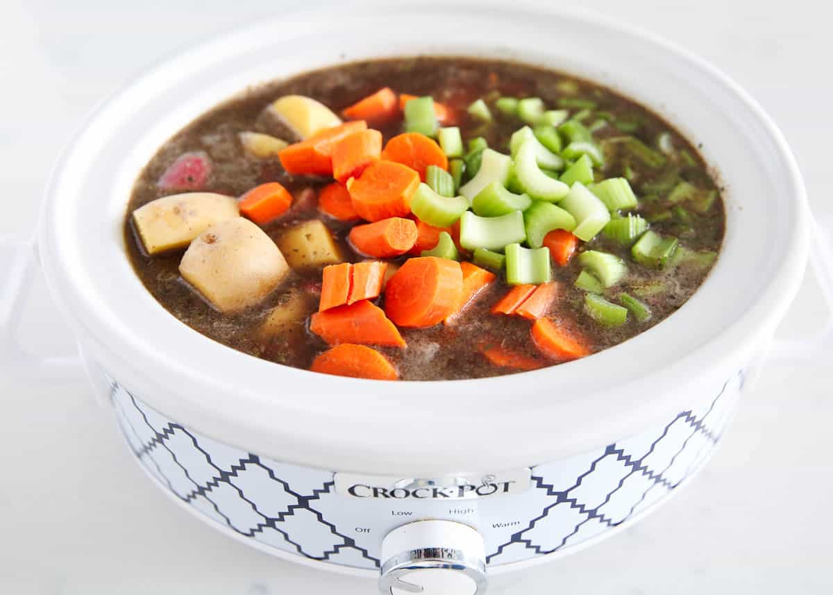 Potatoes, carrots and celery in a crockpot with beef stock.