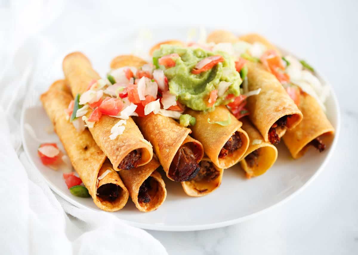 stacked beef taquitos with guacamole and pico on top