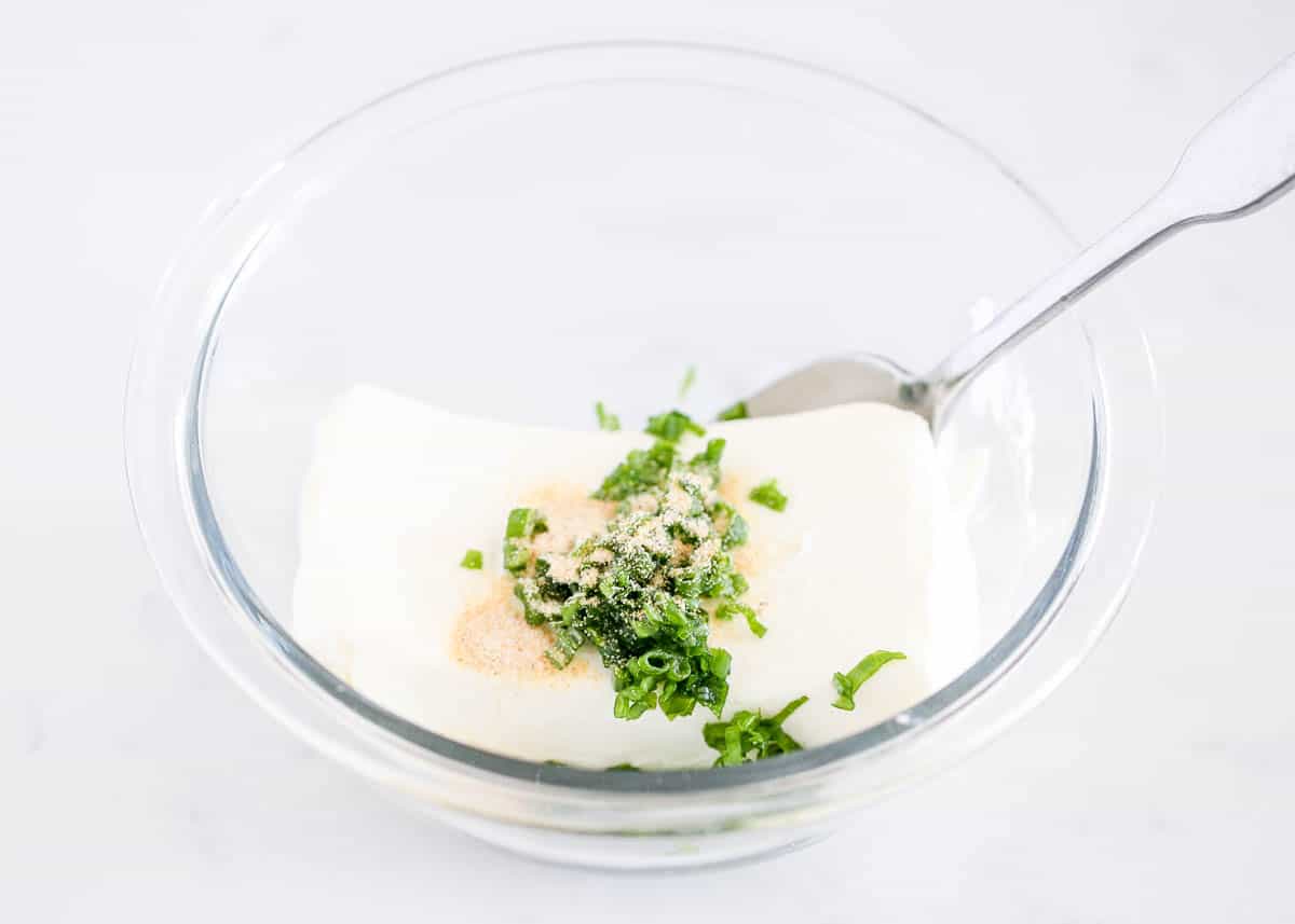 Cream cheese and green onions on bowl.