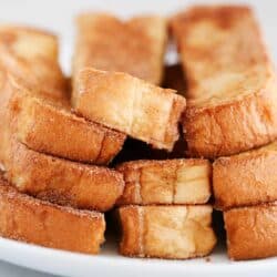 french toast sticks stacked on white plate