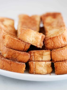 A plate of cinnamon French toast sticks showing thick texture.