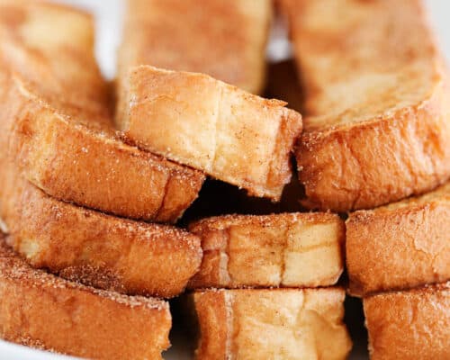 french toast sticks stacked on white plate