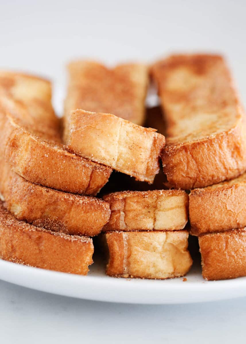 french toast sticks stacked on white plate