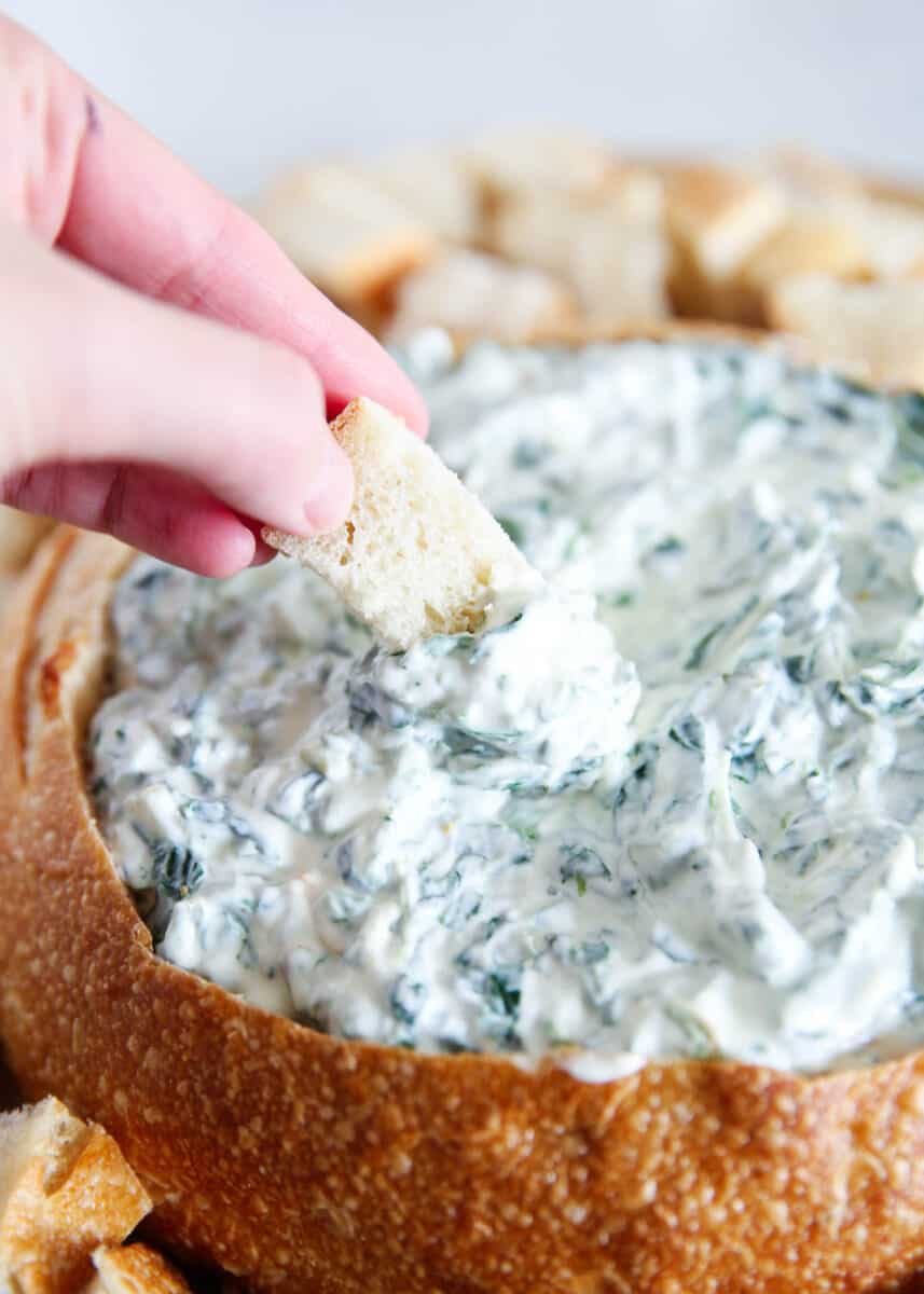 dipping bread into spinach dip