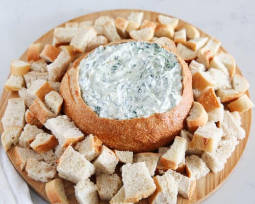 spinach dip inside of bread on board