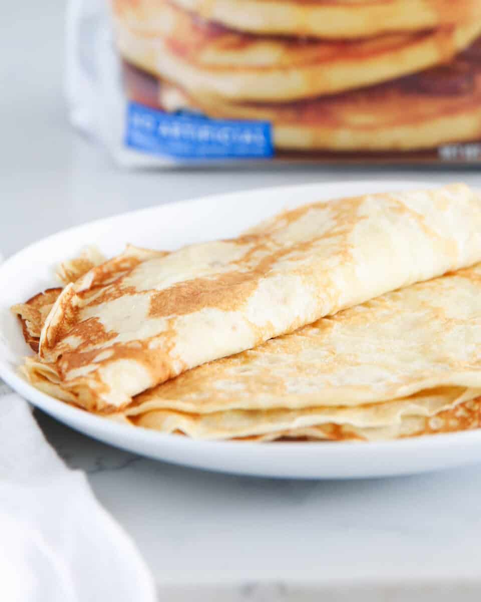 crepes on white plate with pancake mix in background