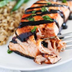 fork taking bite of salmon on plate