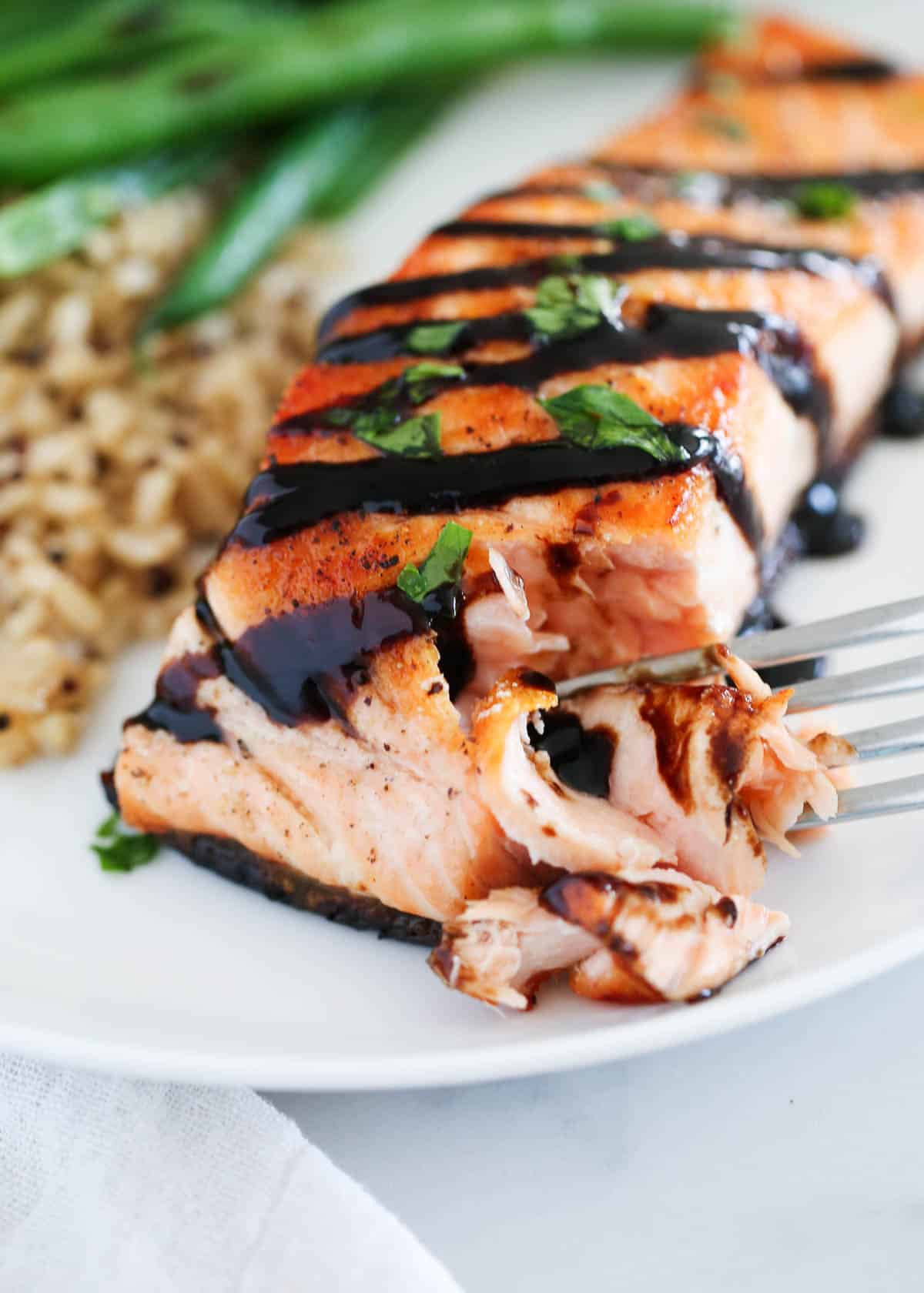 fork taking bite of salmon on plate