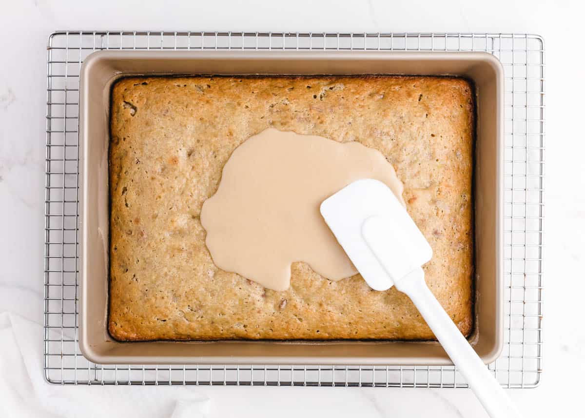 Spreading brown butter frosting on top of banana bread brownies.