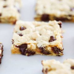 Cake mix cookie bars with gooey chocolate chips cut into squares on a white surface