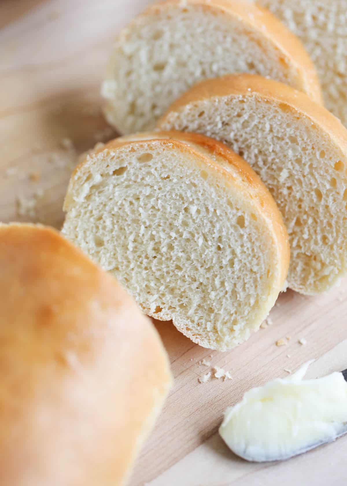 This easy French baguette recipe is a delicious loaf of bread with a golden crust and a soft yet sturdy crumb. There is nothing better than having a basket of crusty homemade bread on your dinner table, except maybe knowing you made it yourself! Sliced French baguette on cutting board.