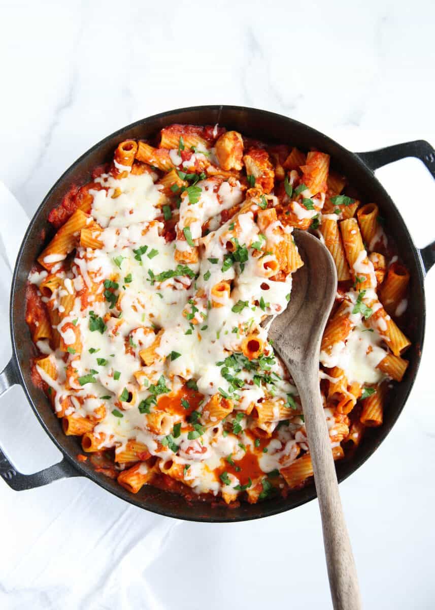One pot chicken parmesan pasta is a true comfort meal composed of delicious Italian flavors including seasoned chicken, pasta, sauce, and lots of cheese! It's all the best parts of a classic chicken parm made into a 30-minute one-pan meal! one pot chicken parmesan pasta on counter