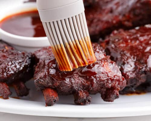 brushing sauce on top of ribs