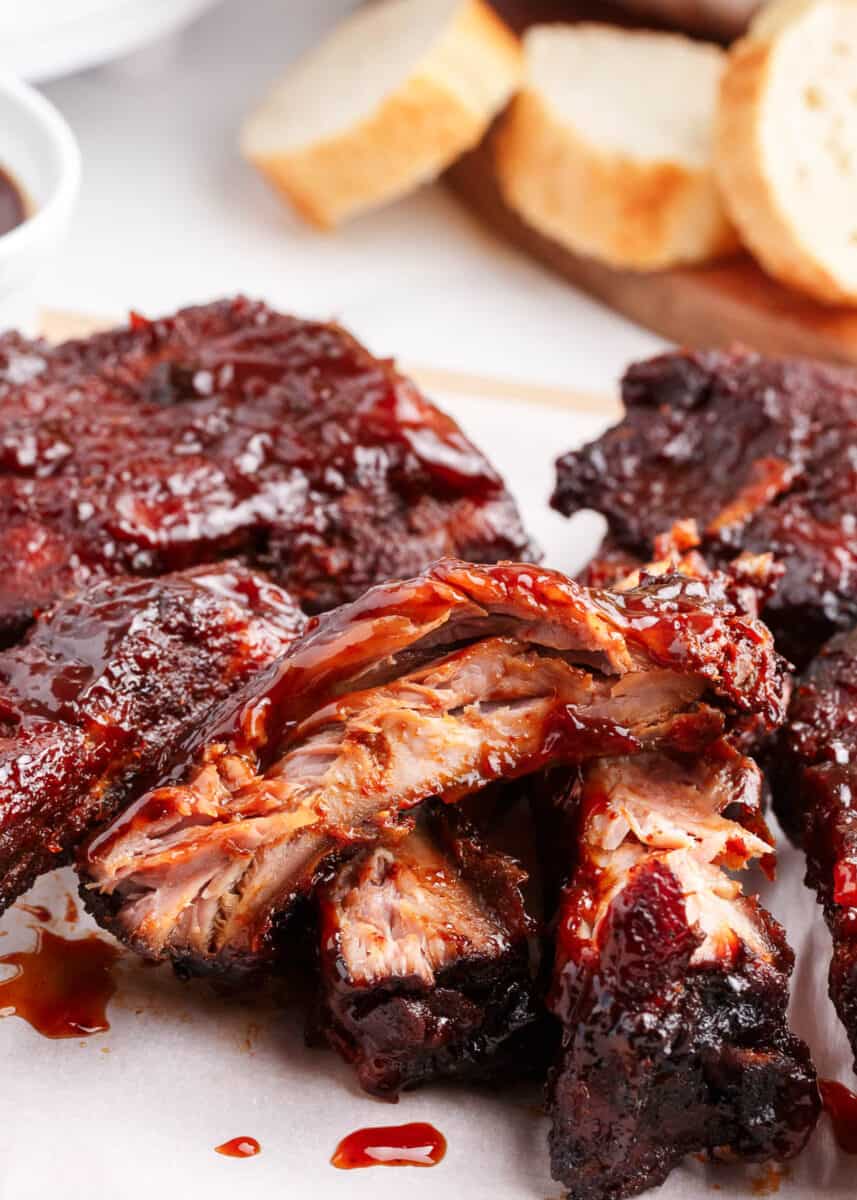 Slow Cooker Ribs - Easy baby back ribs smothered with a homemade rub and sweet and tangy barbecue sauce. Cooked to perfection in the crockpot and fall off the bone delicious. These are the best slow cooker ribs! slow cooker ribs on paper