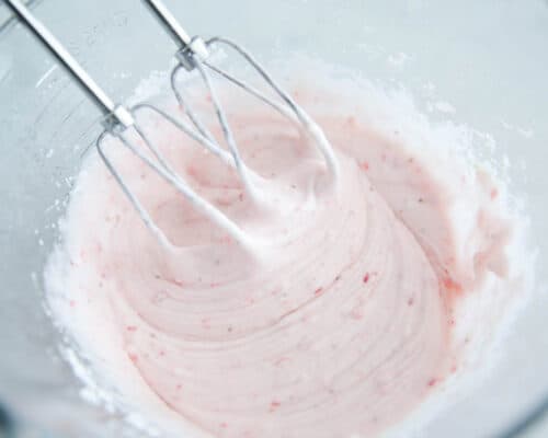 mixing strawberry cream cheese frosting in bowl