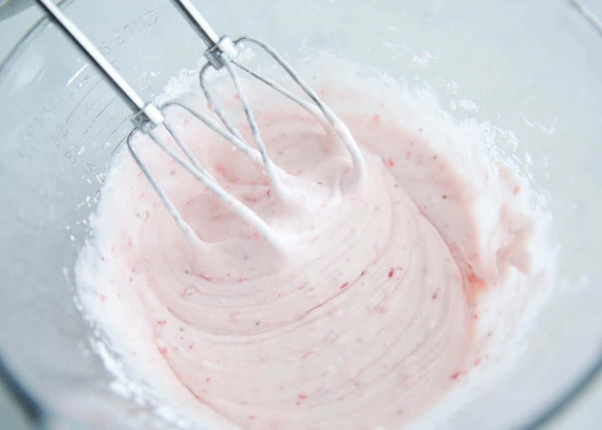 mixing strawberry cream cheese frosting in bowl