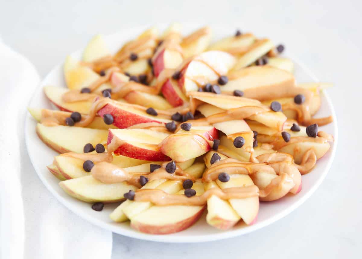 This apple nachos recipe is made with crisp sliced apples topped with melted peanut butter, honey, and a sprinkling of chocolate chips. It takes one of my favorite healthy snack ideas and turns it into a healthy treat! apple nachos on plate