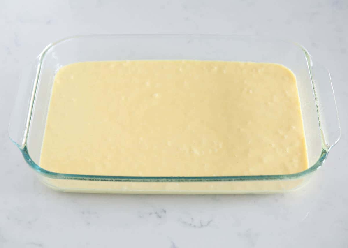 Lemon cake mix batter in a pan ready to bake for a lemon poke cake.