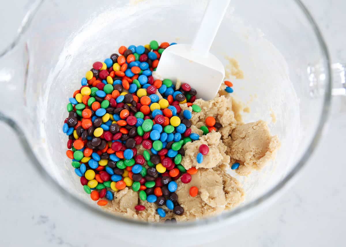 Mixing m&m's into cookie dough.
