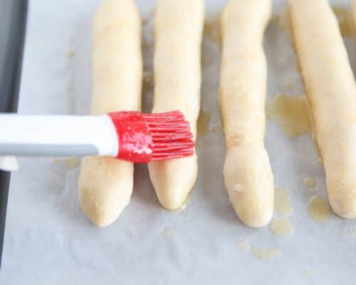 brushing melted butter on bread sticks