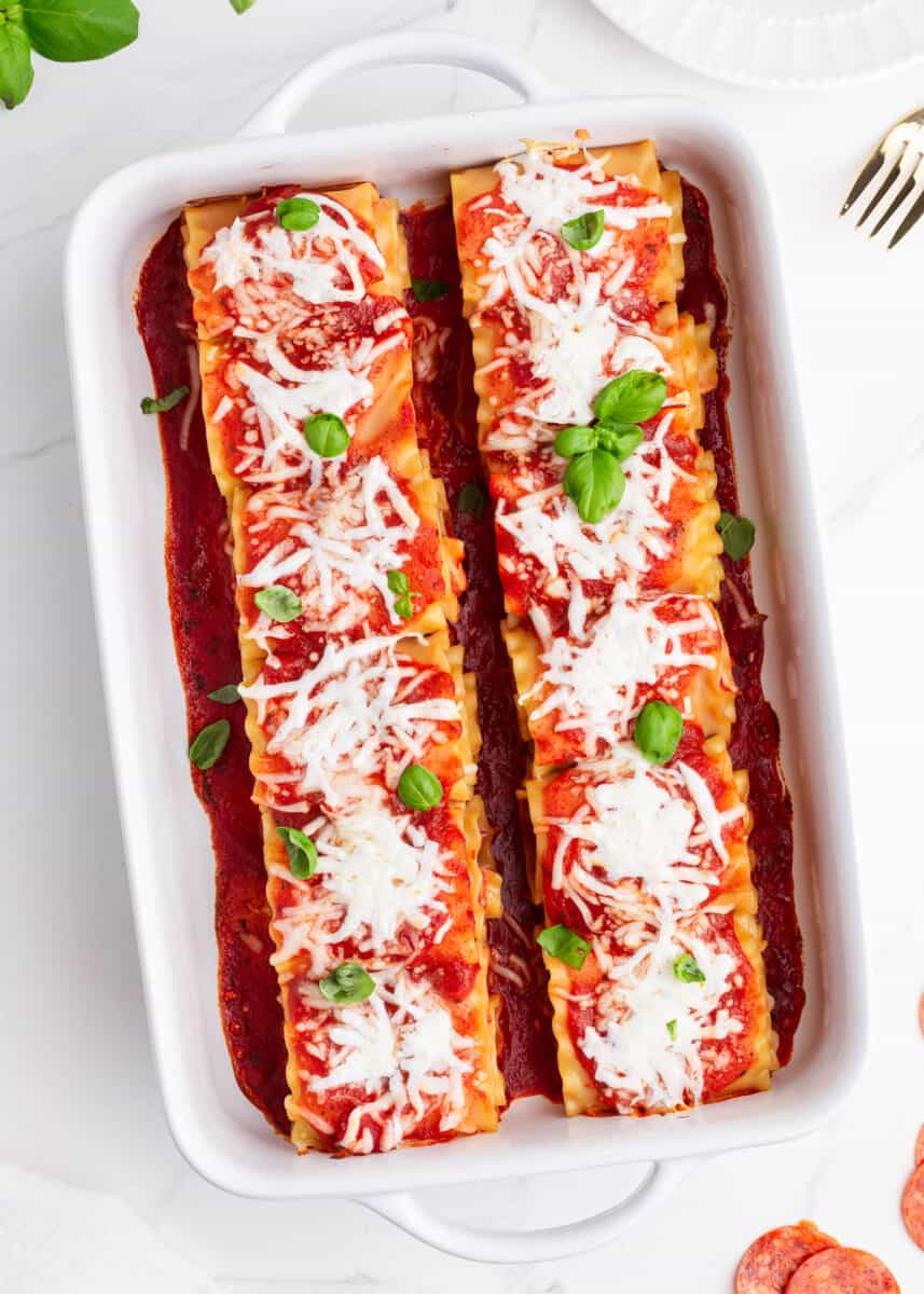 All of the flavors of pepperoni pizza and traditional lasagna combined into one delicious creation. These pepperoni lasagna roll ups are easy to make, ready in 30 minutes and will be a hit with your family! pepperoni lasagna roll ups inside of baking sheet