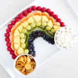 rainbow fruit platter on white plate with gold coins