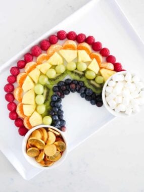 rainbow fruit platter on white plate with gold coins