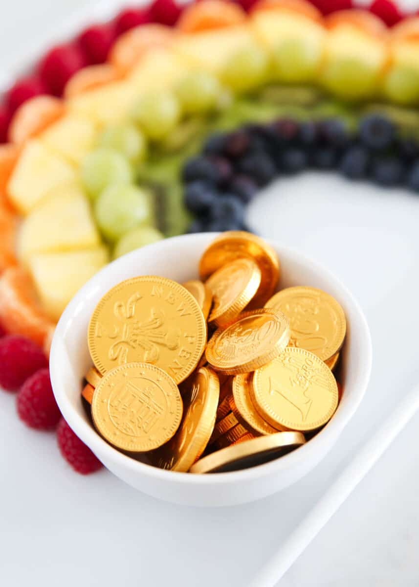 rainbow fruit platter on white plate with gold coins