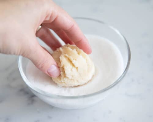 rolling sugar cookie dough ball in sugar