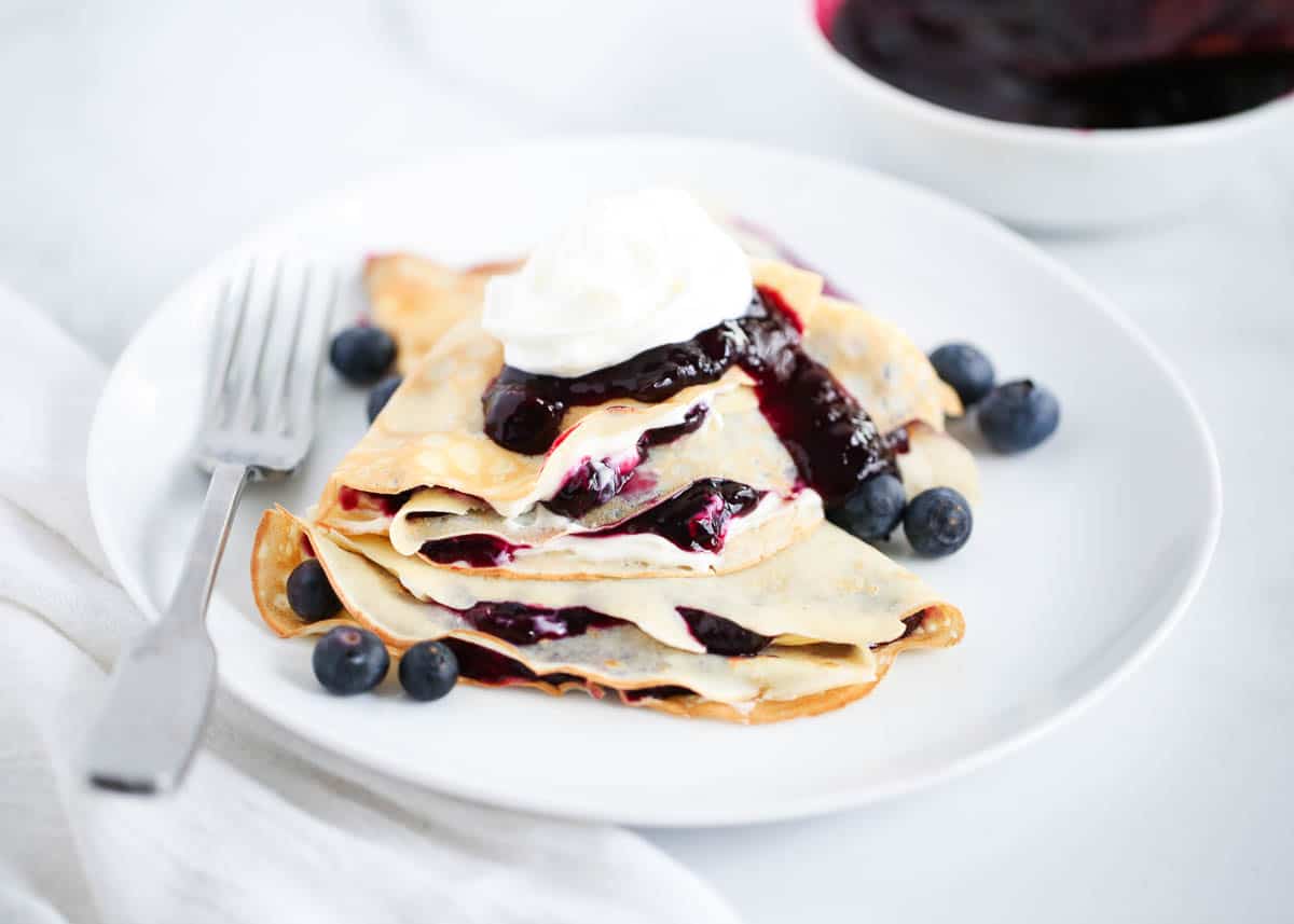 Stacked blueberry crepes on white plate