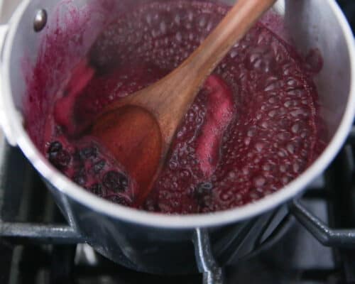 stirring blueberry sauce in a pot