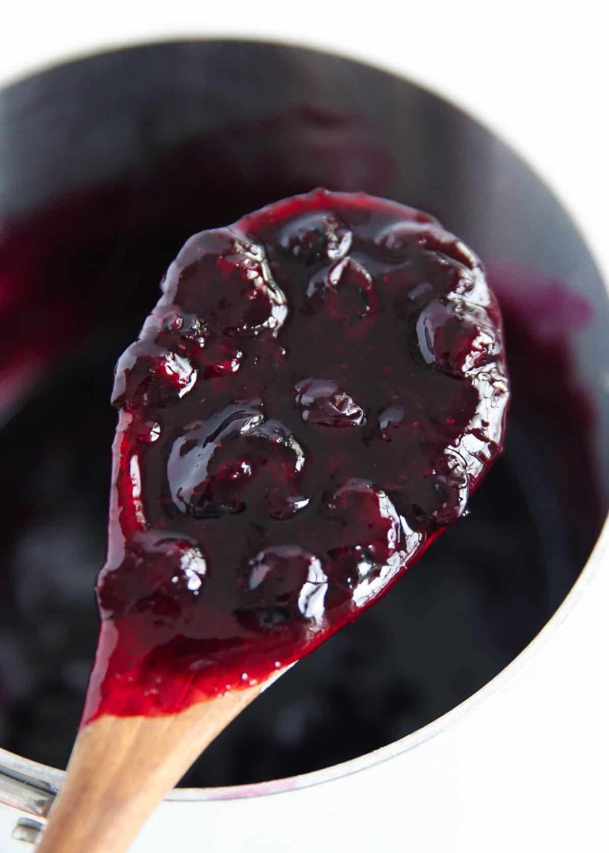Easy homemade blueberry sauce on a wooden spoon.