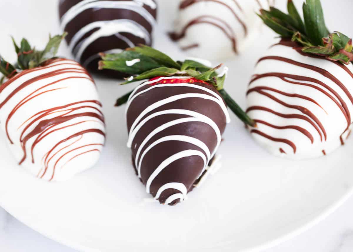 Chocolate covered strawberries on white plate.