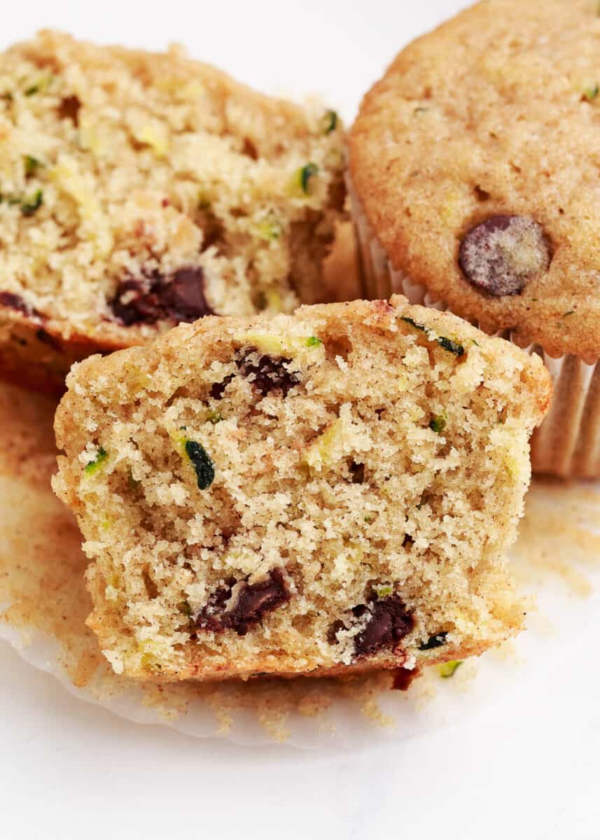 Open zucchini chocolate chip muffins unwrapped from a muffin wrapper.
