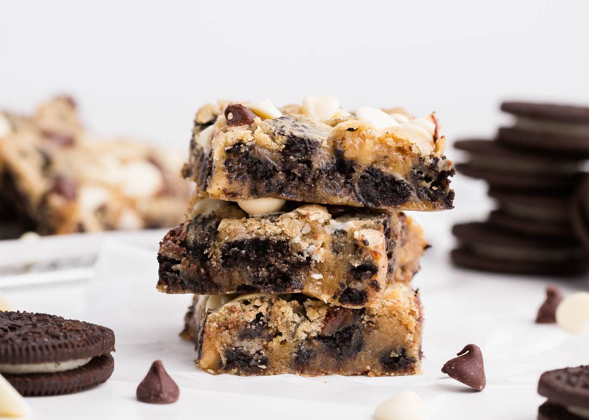 Soft and gooey Oreo cookie bars filled with crushed Oreo cookies and white chocolate chips. Every bite of this decadent dessert is chewy, thick and filled with chocolate! Stack of oreo cookie bars.
