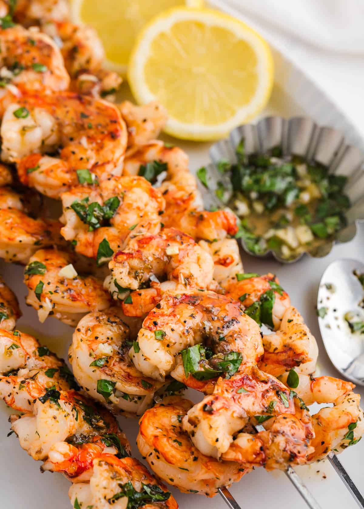 Grilled shrimp on a skewer on a white platter. 