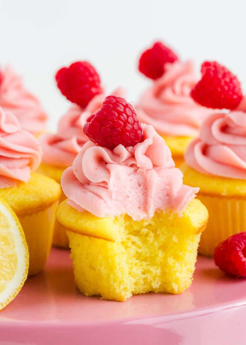 Frosted lemon raspberry cupcake with a bite taken out. 