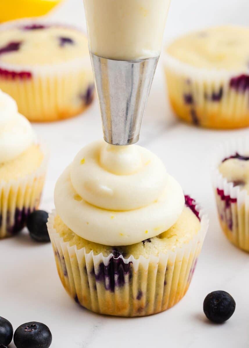 Piping lemon frosting on cupcakes.