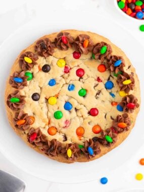 M&M cookie cake on white plate.