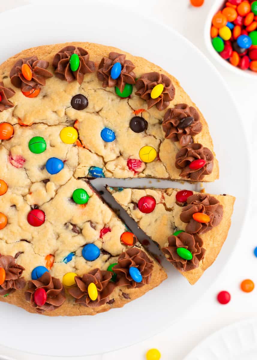 Cookie cake with a slice taken on a white plate.