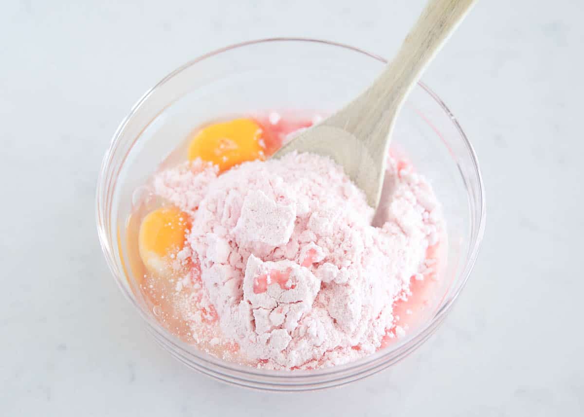 Stirring together strawberry cake mix, oil and eggs for strawberry brownies.